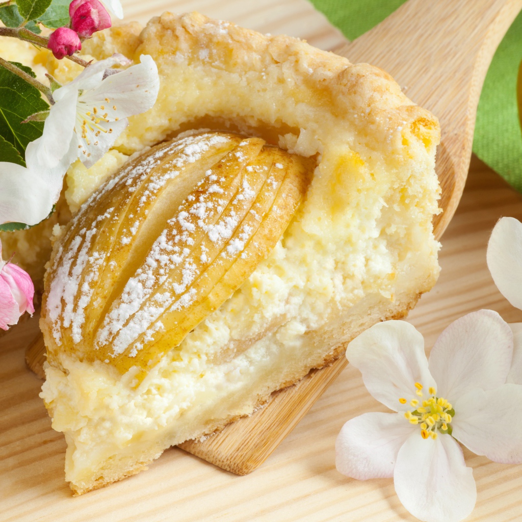 Кусок пирога с яблоками на деревянной лопатке с цветами яблони