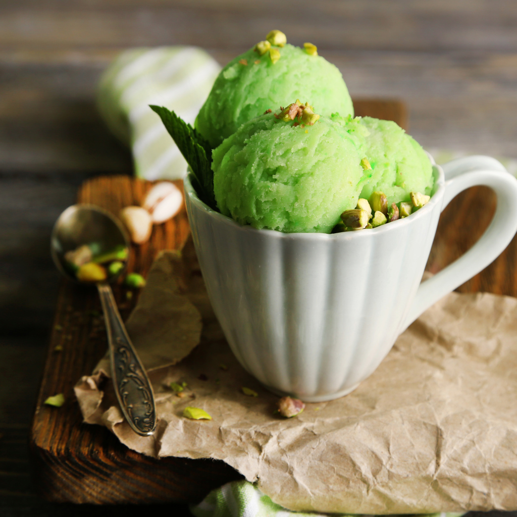 Фисташковое мороженое в белой чашке на столе