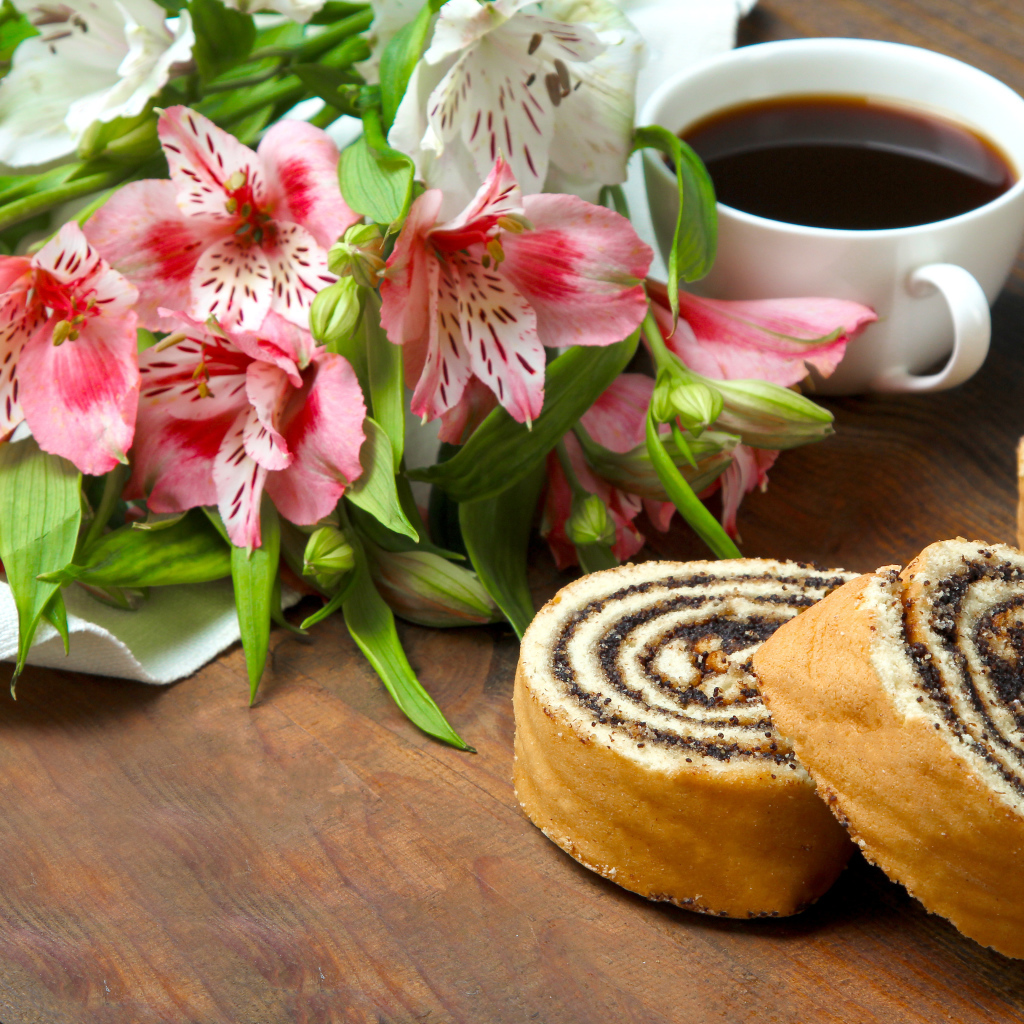 Рулет с маком на столе с цветами альстрёмерия и чашкой кофе