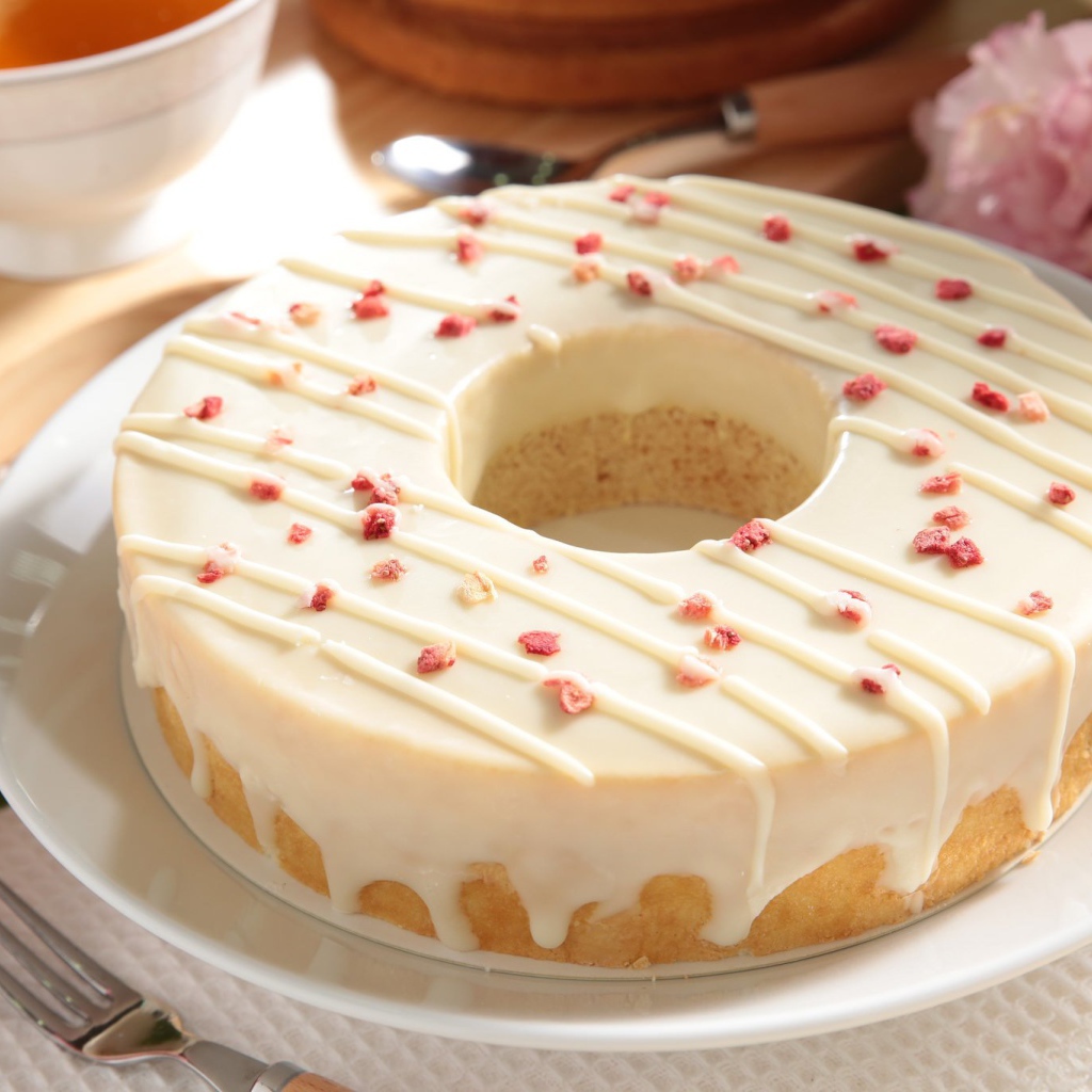 Круглый кекс с глазурью на белом блюде 