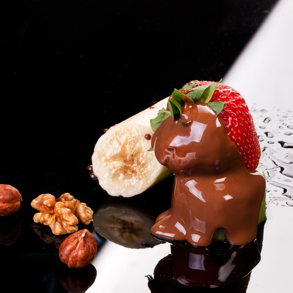 Клубника в шоколаде, банан и орехи на черной поверхности
