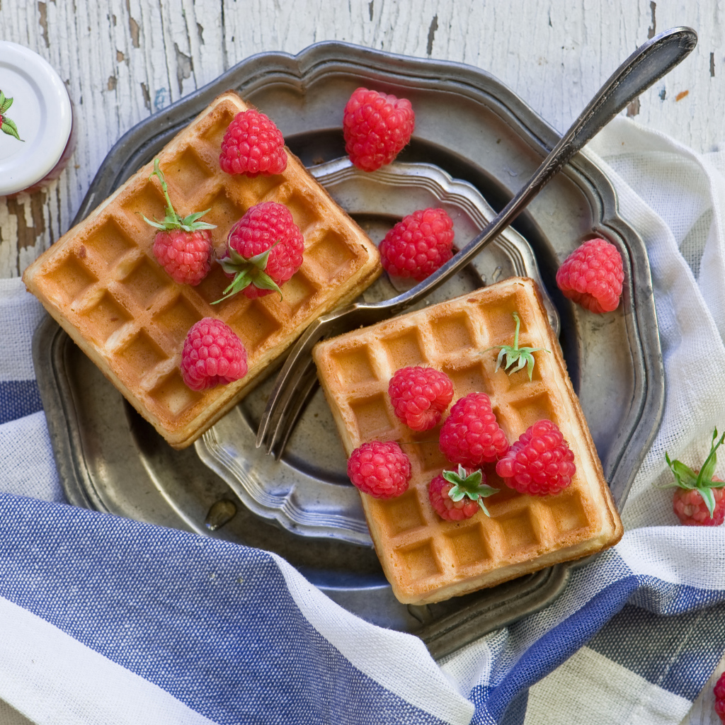 Сладкие вафли с ягодами малины на столе 