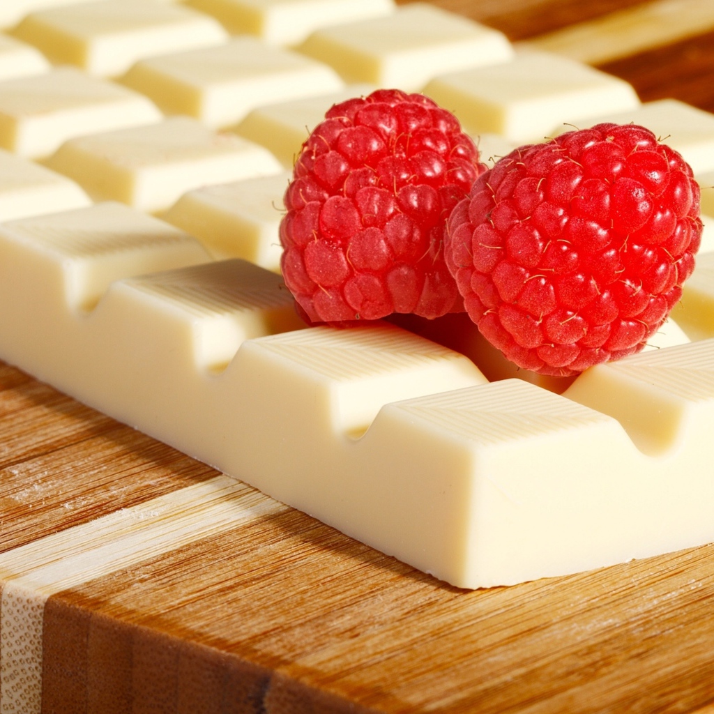 Сладкий белый шоколад с ягодами малины на столе