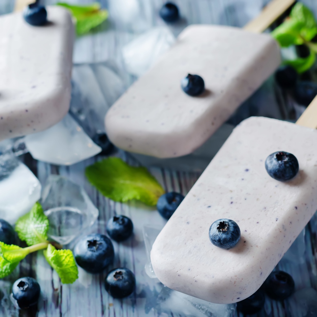 Вкусное мороженое с ягодами черники на столе с кусочками льда