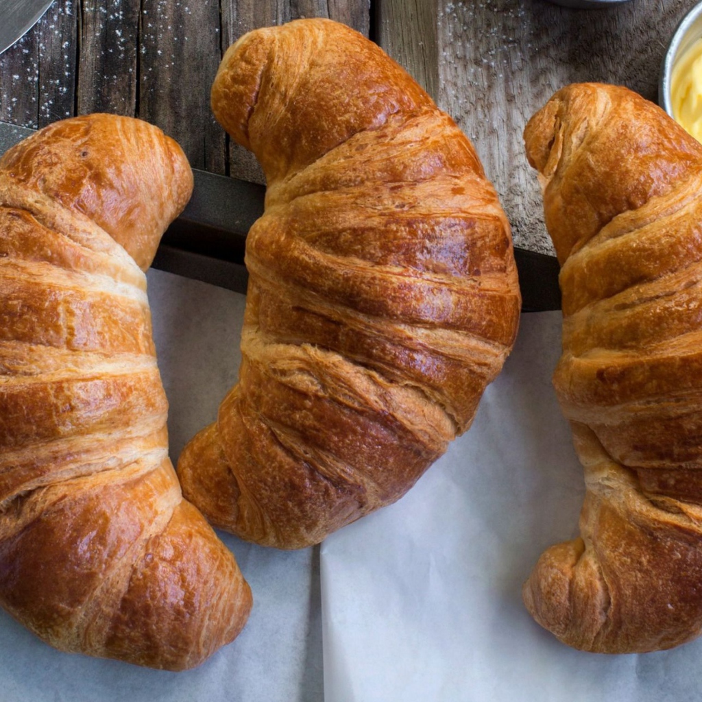 Три свежих круассана на столе с кремом 