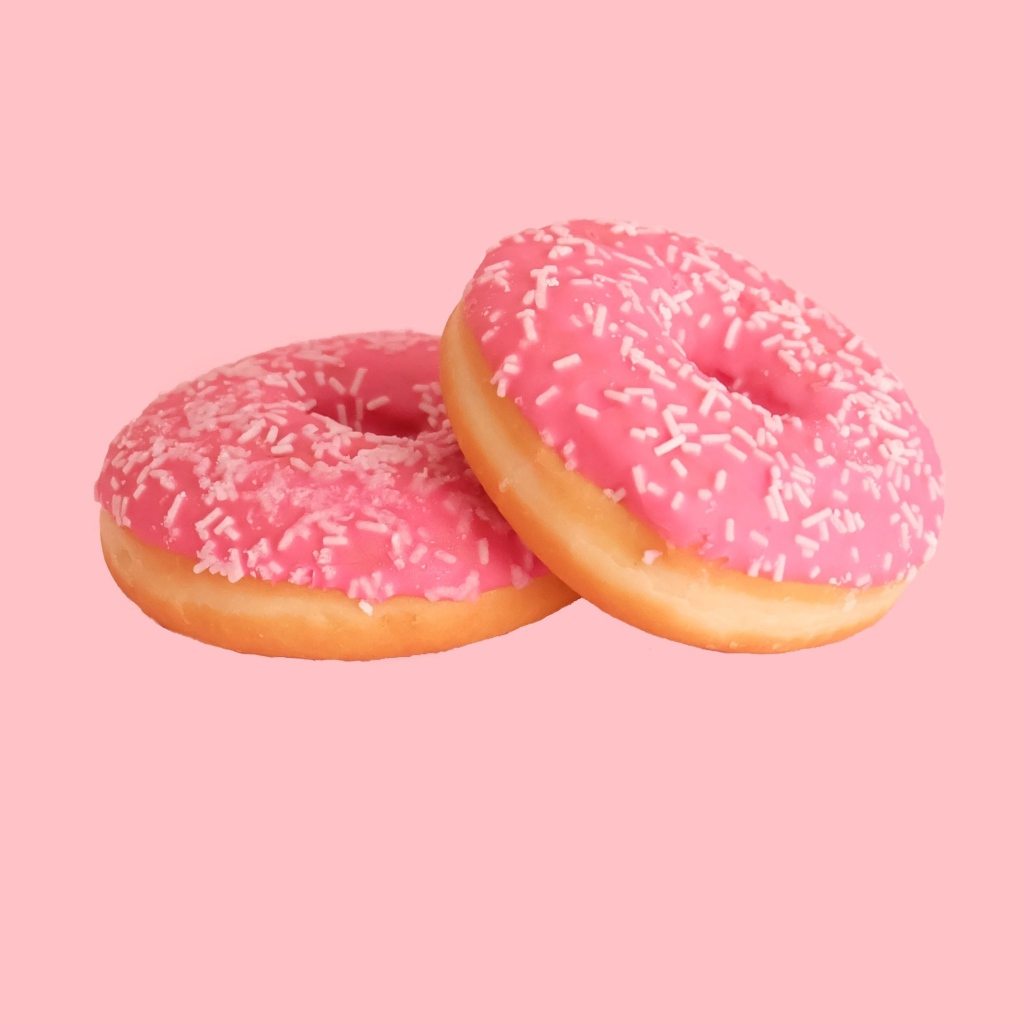 Два пончика с глазурью на розовом фоне