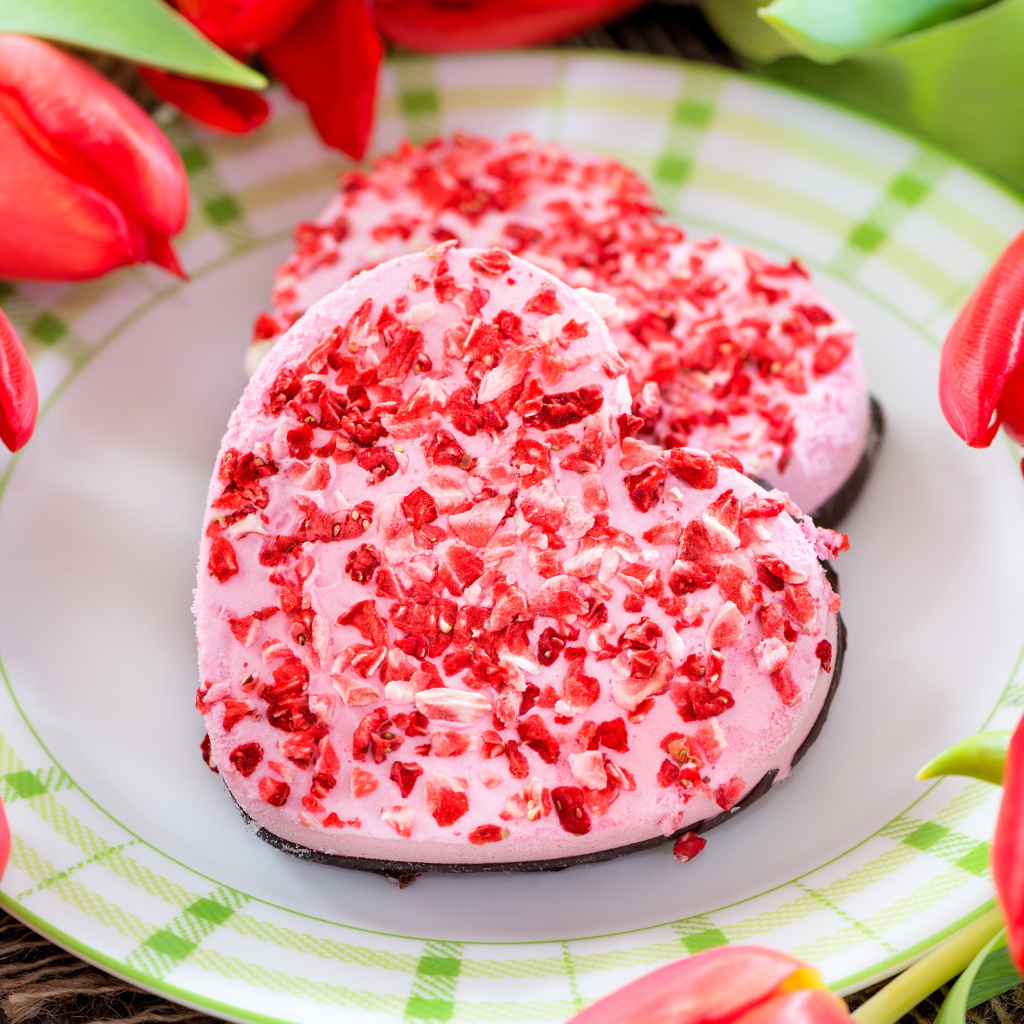 Два печенья в форме сердца на тарелке с тюльпанами 