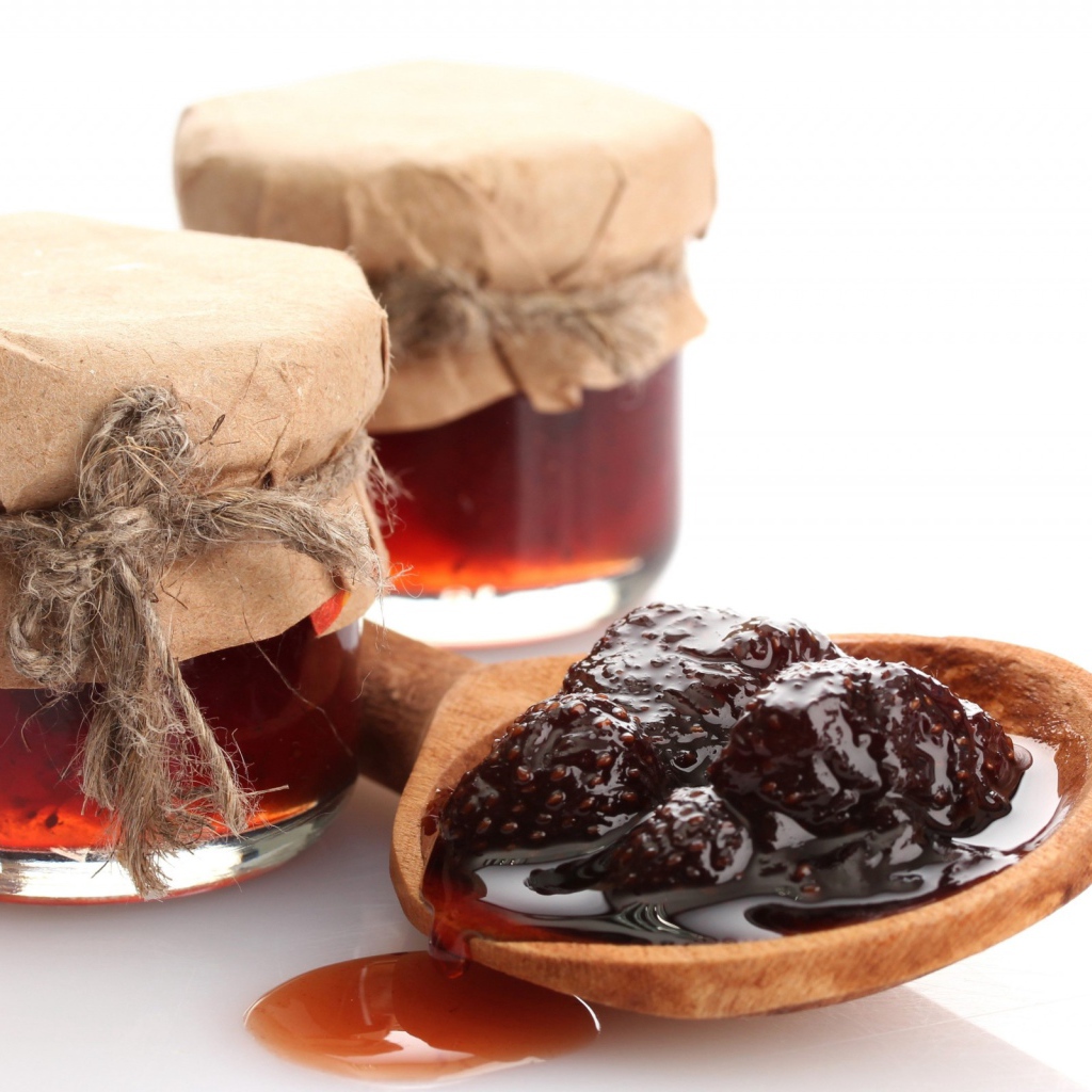 Две банки клубничного варенья на столе с ложкой 