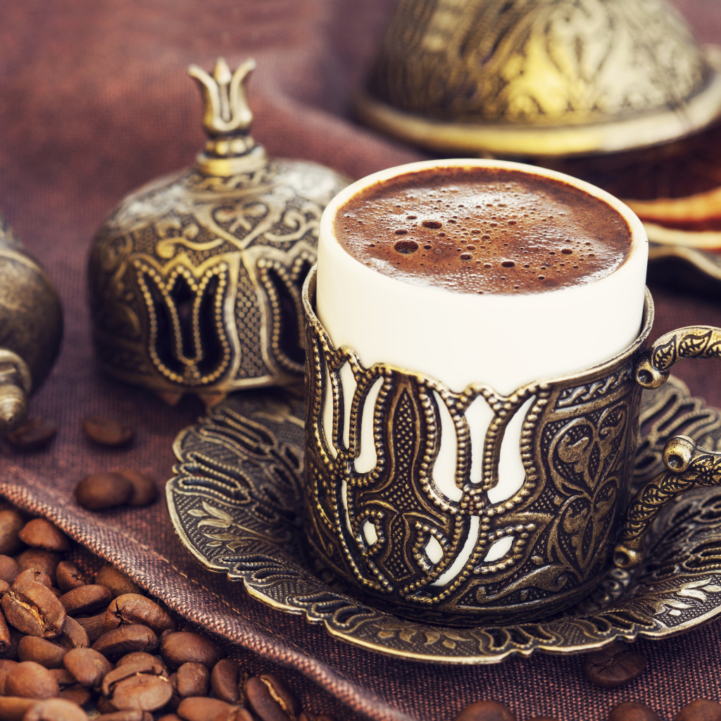 Красивая дизайнерская чашка кофе на столе с зернами