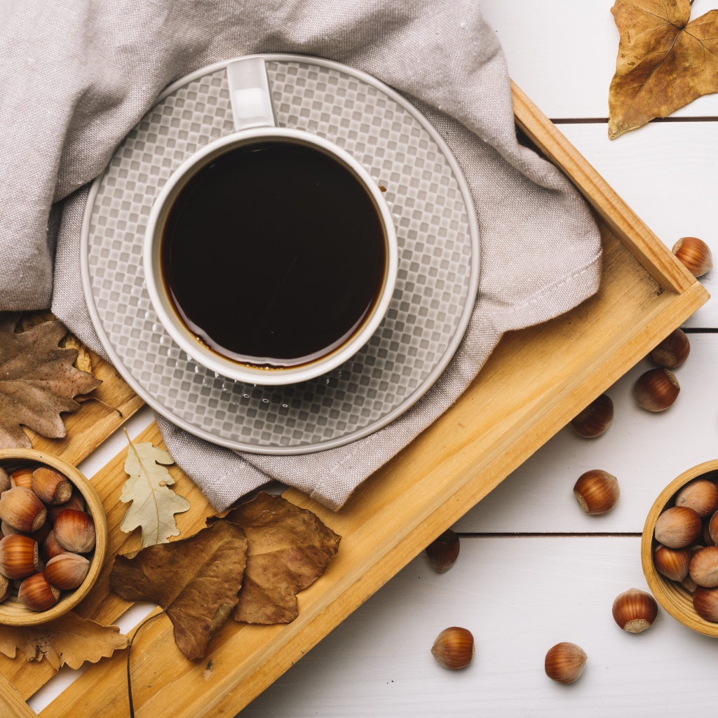 Чашка кофе на столе с лесными орехами и желтыми листьями