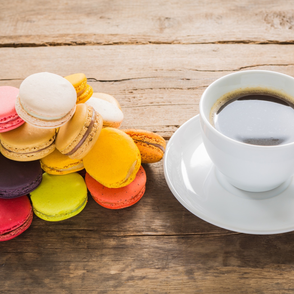 Чашка кофе на столе с разноцветными макарунами