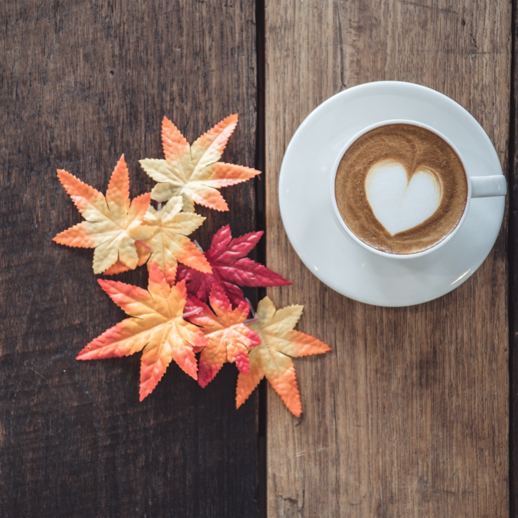 Чашка кофе на деревянном столе с желтыми листьями