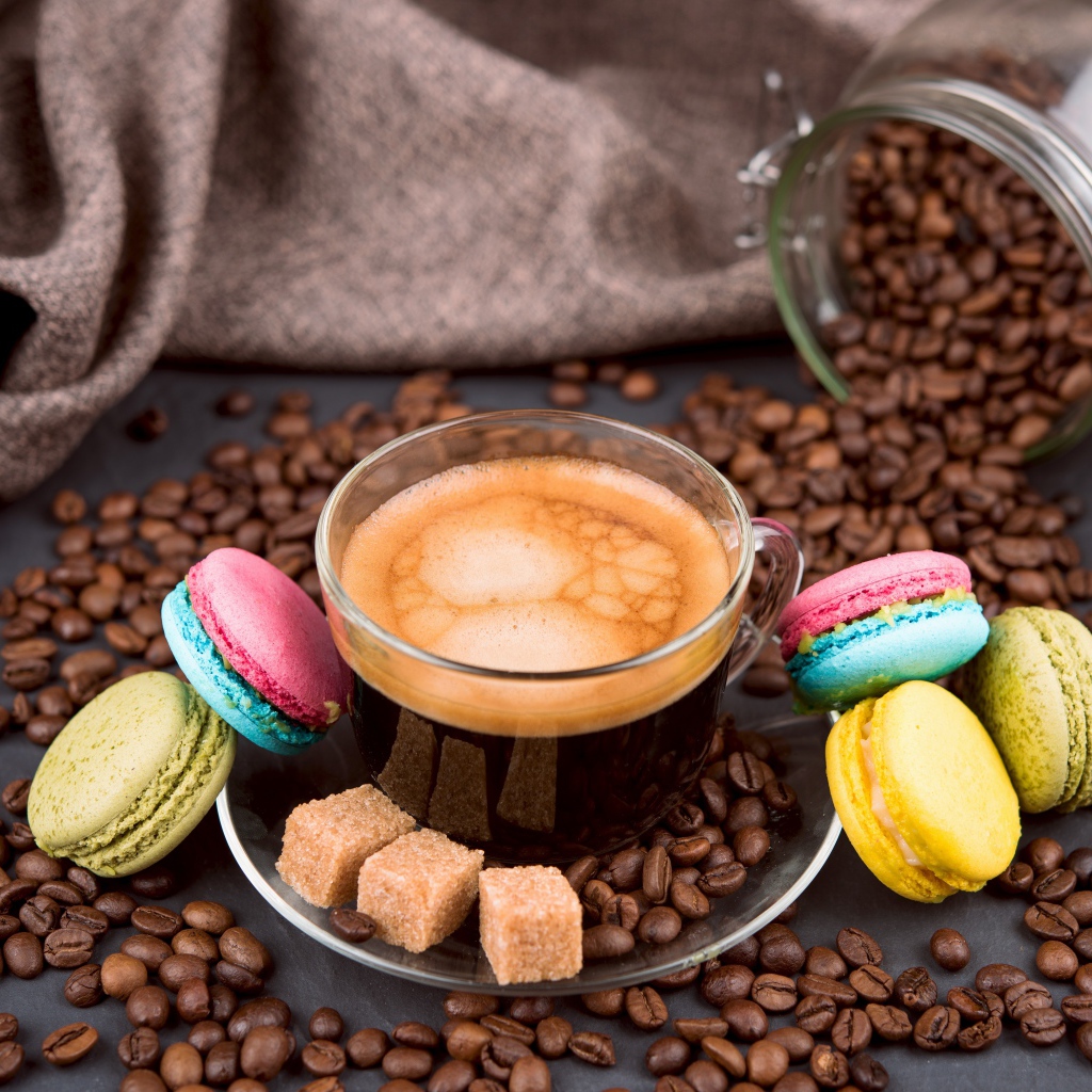 Чашка кофе с кофейными зернами, кубиками сахара и десертом макарон