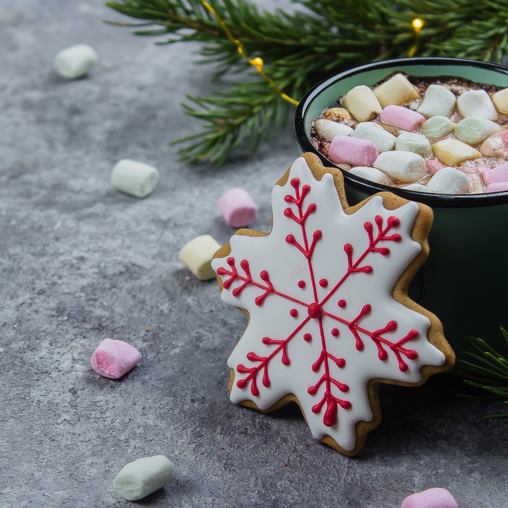 Чашка горячего напитка с кусочками маршмеллоу на столе с печеньем 