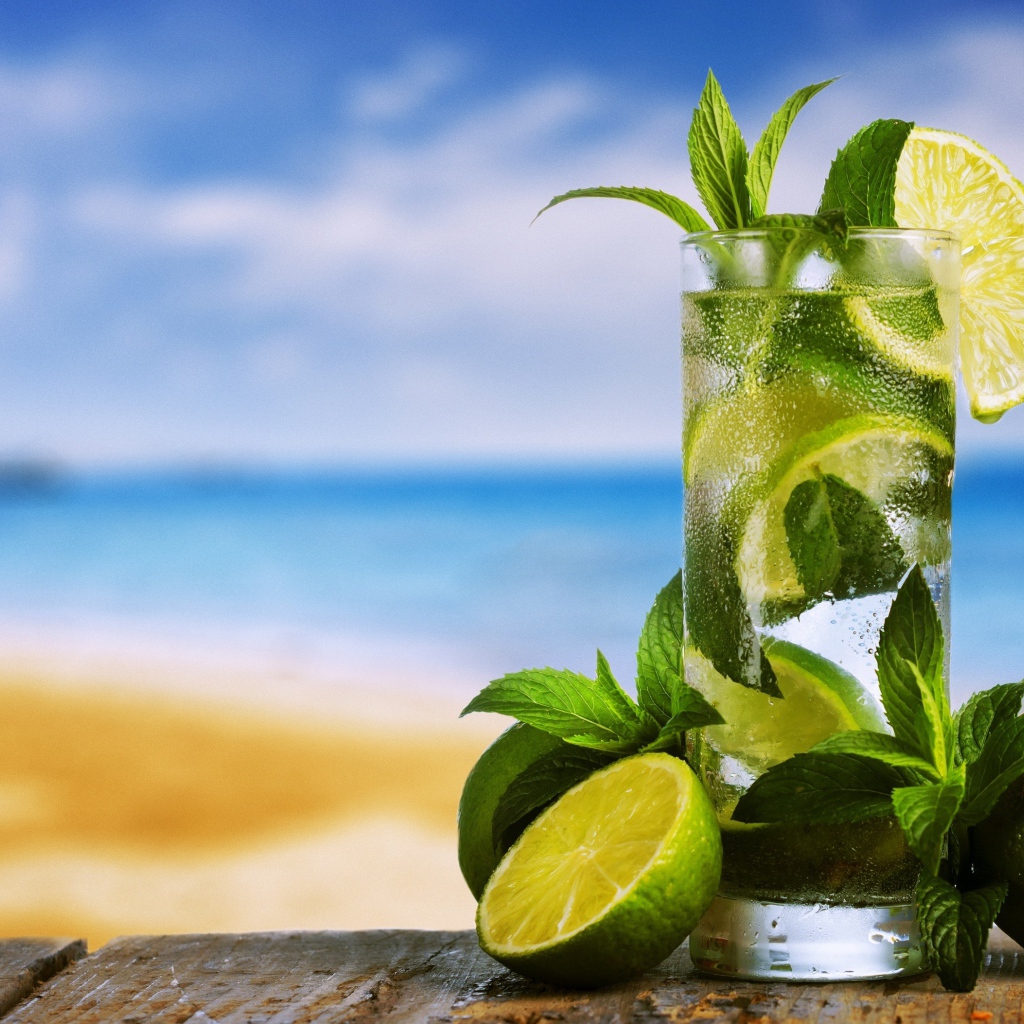 Стакан холодного мохито на столе с мятой и лаймом