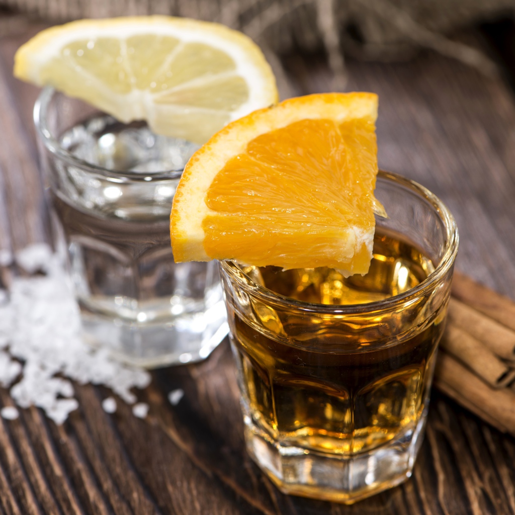 Рюмка водки и рюмка виски на столе с кусочками лимона