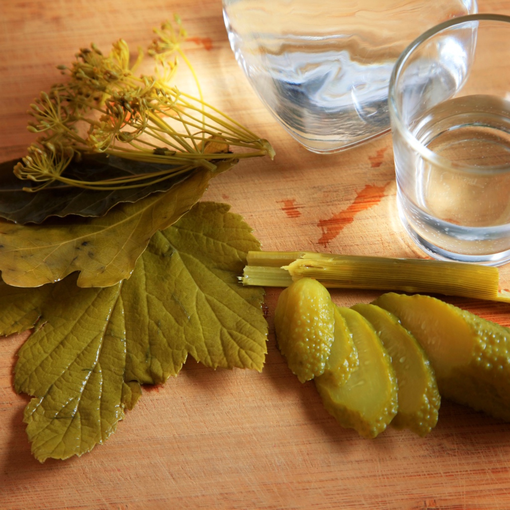 Рюмка водки на столе с соленым огурцом