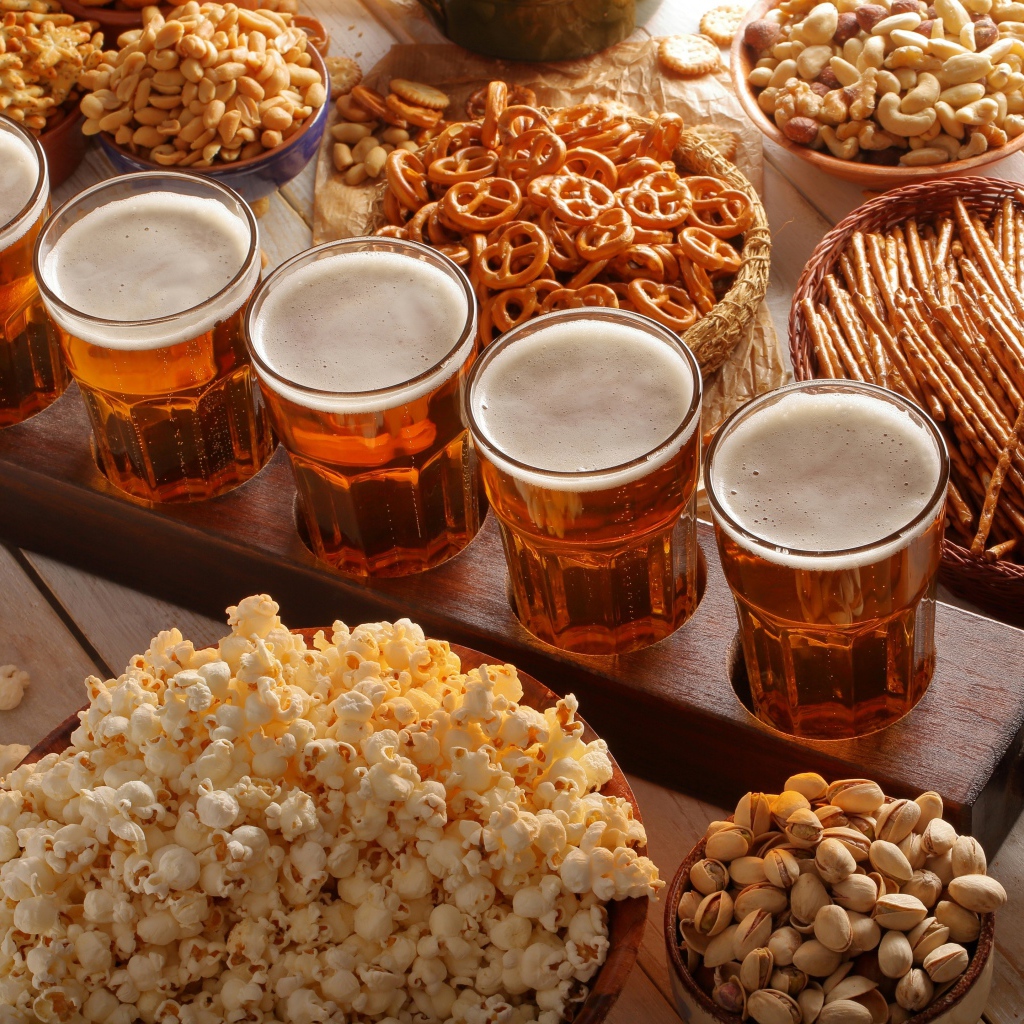 Пиво с орешками, фисташками, попкорном и печеньем на столе