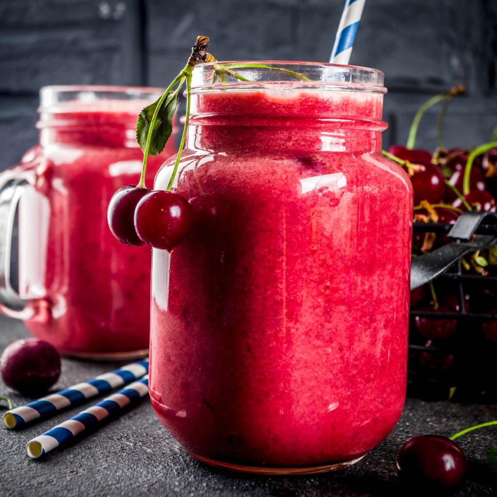 Вишневое смузи в стеклянной банке на столе с ягодами