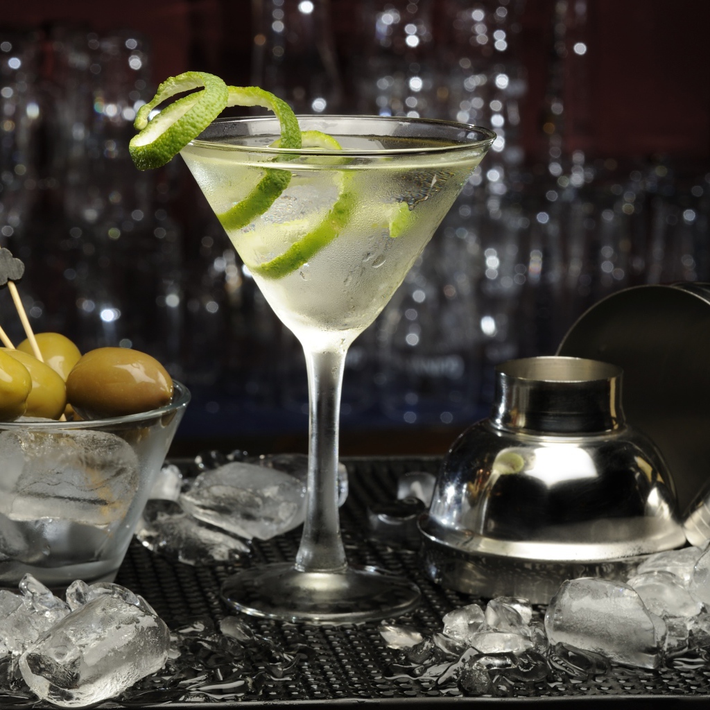 Коктейль с лаймом на столе с оливками и кубиками льда