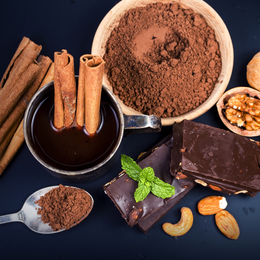 Какао с корицей, орехами и шоколадом на столе 