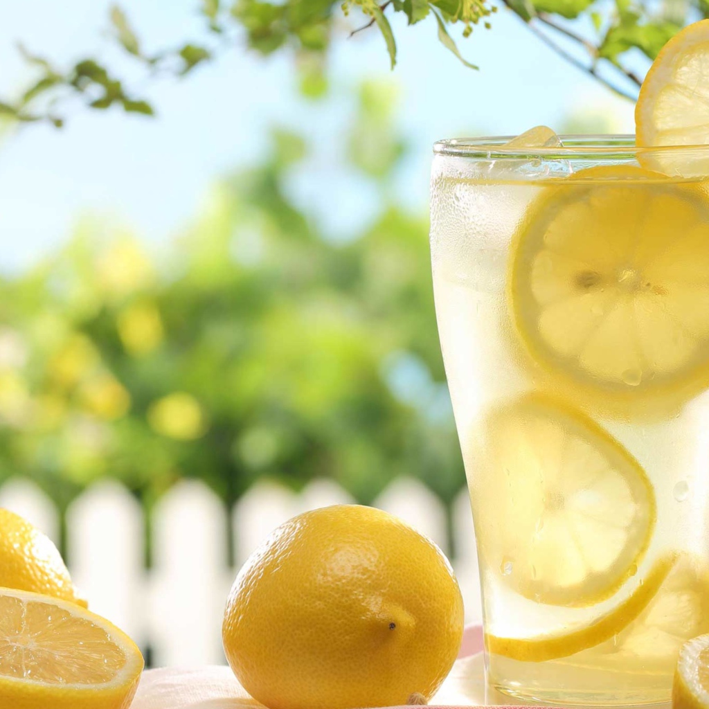 Холодный лимонад в стакане с кусочками лимона