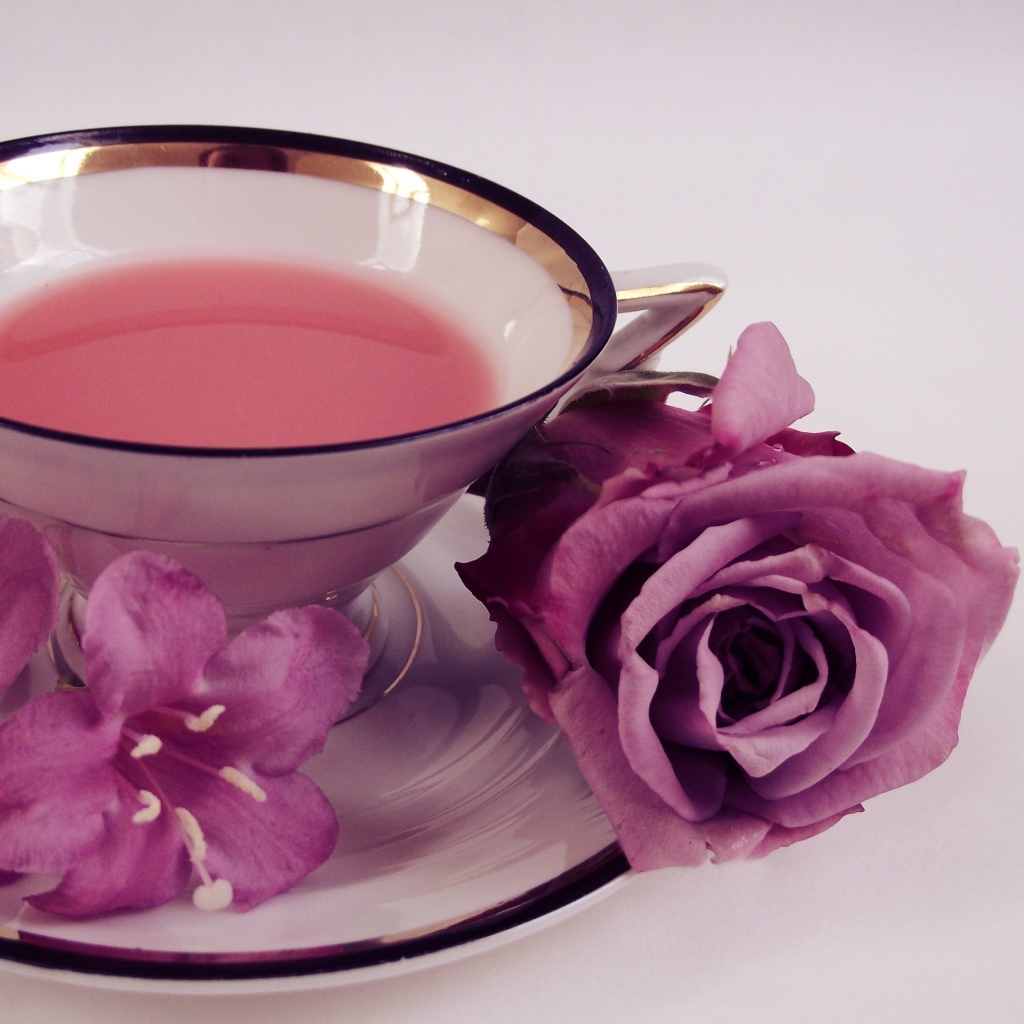 Чашка чаю на тарелке с розой и колокольчиками на сером фоне