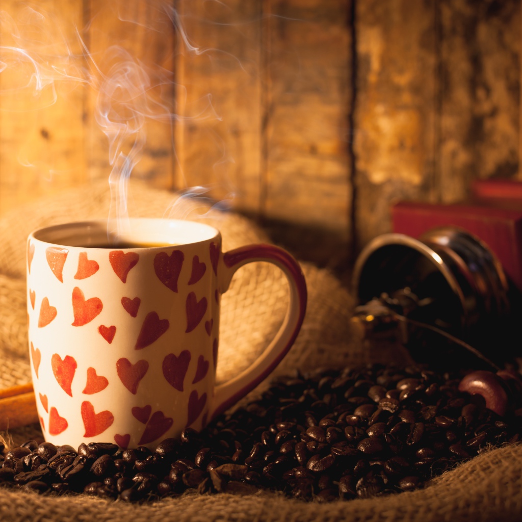 Чашка с горячим кофе на столе с кофейными зернами и корицей