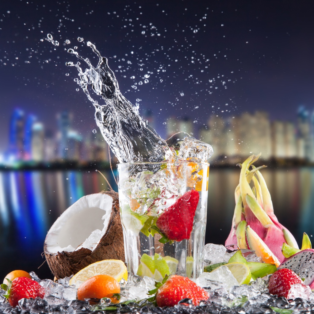 Напиток в стакане с тропическими фруктами на фоне ночного города