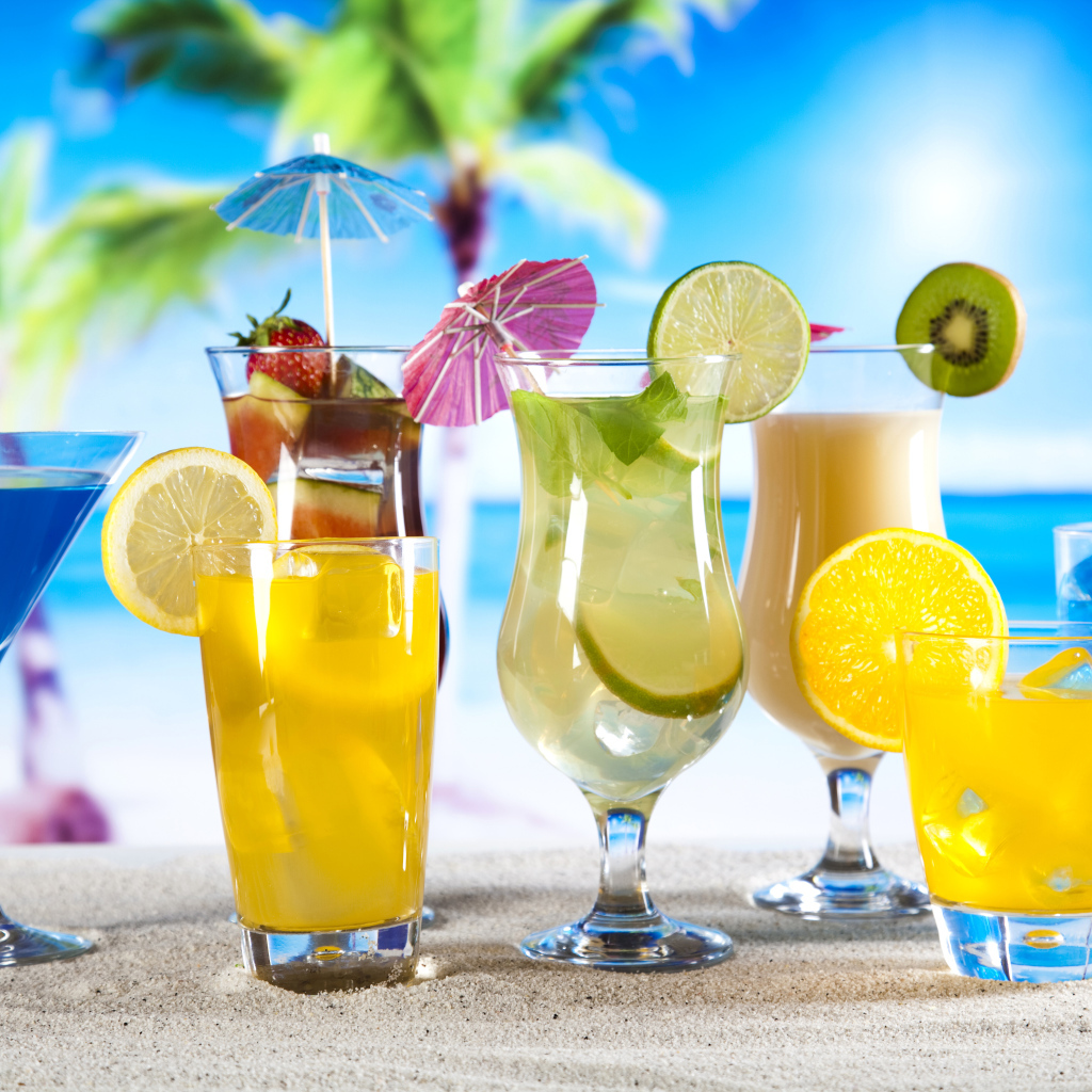 Бокалы с тропическими коктейлями на песке на пляже