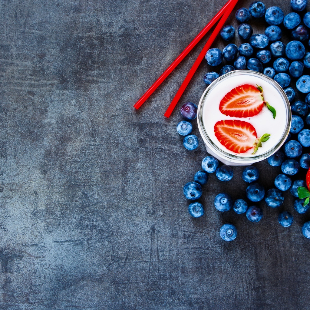 Молочный коктейль с клубникой и черникой на столе 