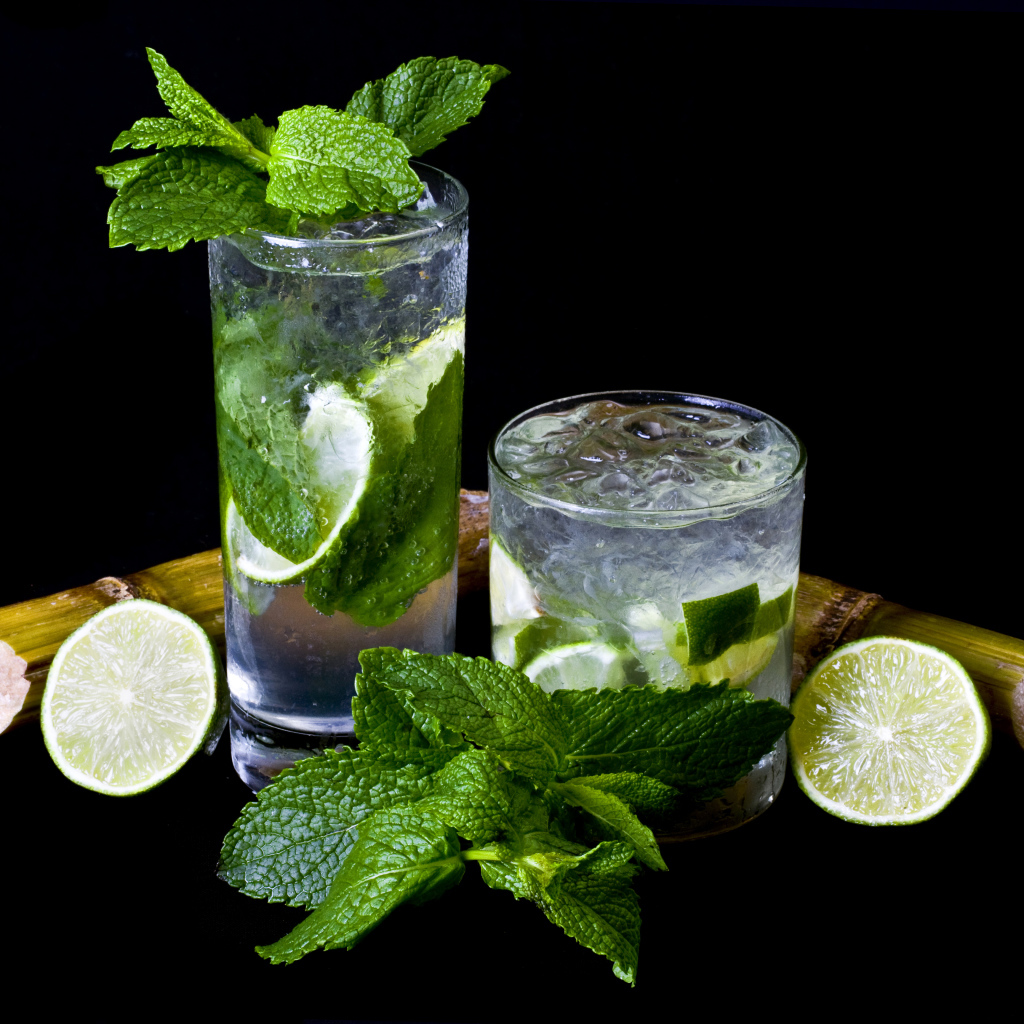 Напиток мохито в стаканах с лаймом и листьями мяты на черном фоне