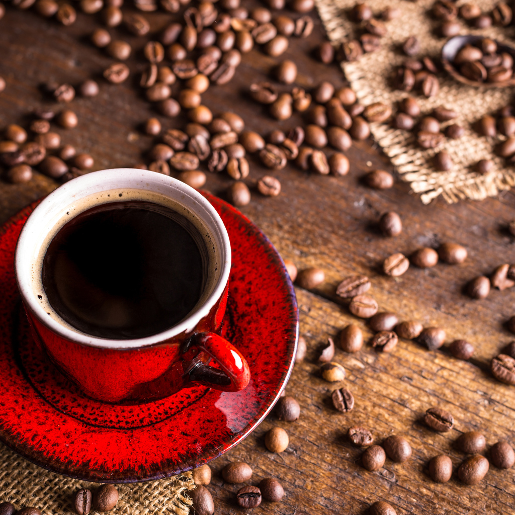 Красная чашка кофе на столе с зернами кофе