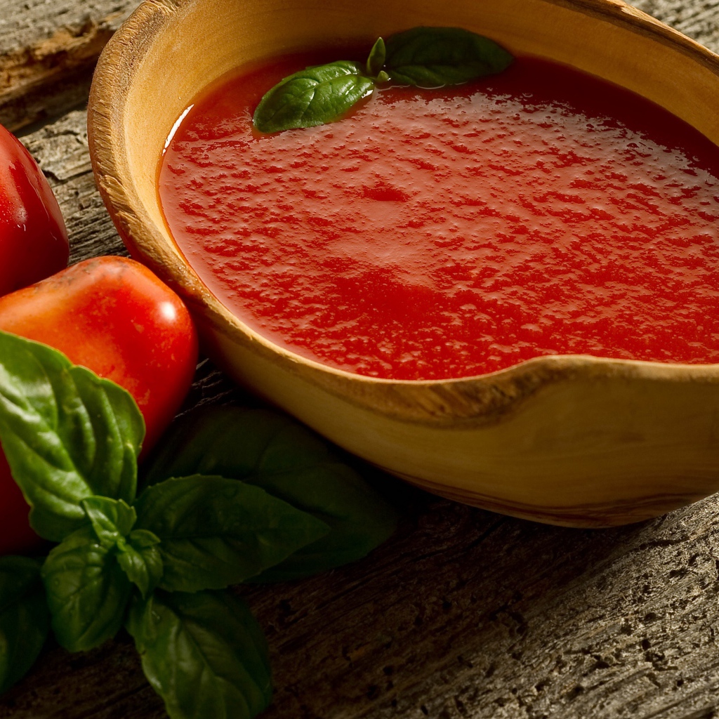 Томатный сок в деревянной посуде на столе с помидорами и базиликом