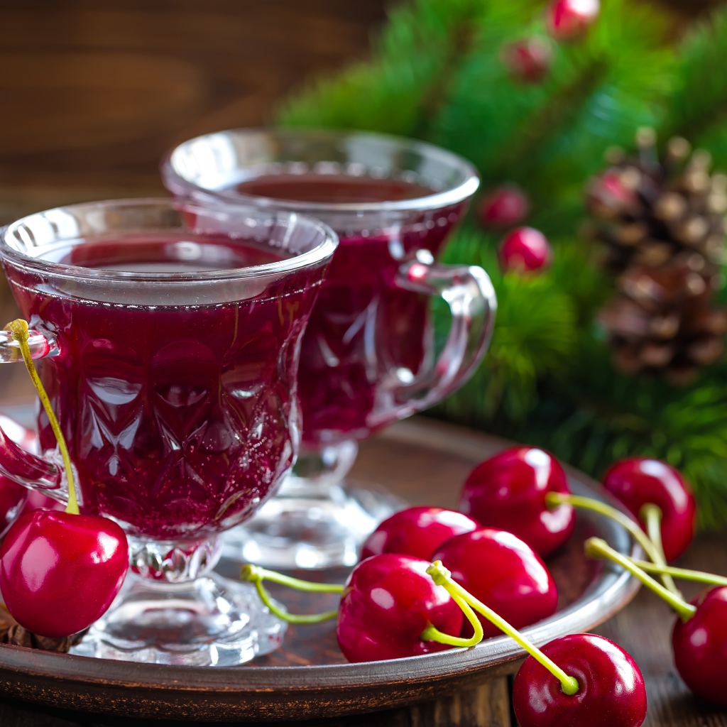 Две чашки вишневого сока со свежими вишнями на столе