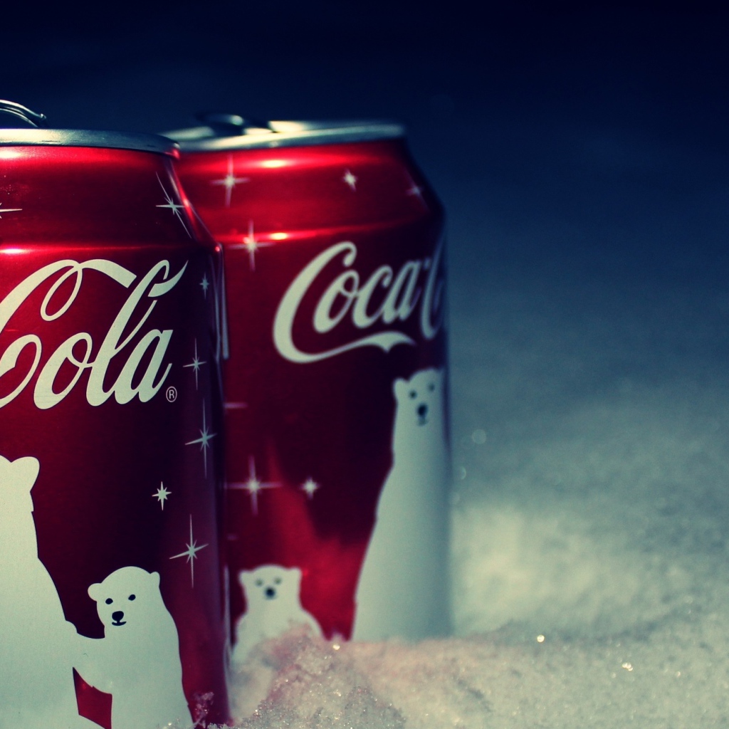 Две красные банки напитка Кока Кола стоят на снегу
