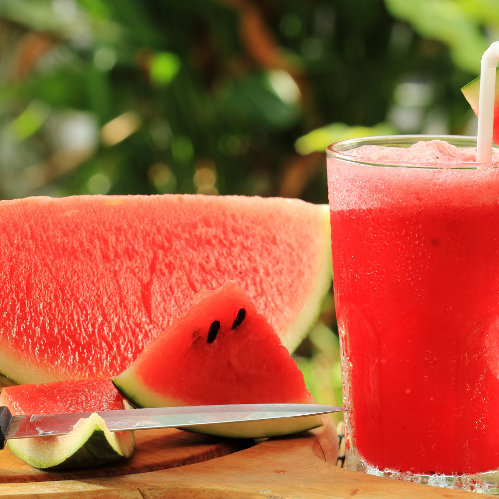 Арбузный напиток в стакане на столе с куском арбуза