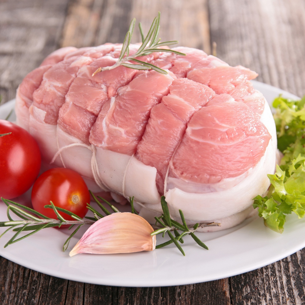 Кусок свежего мяса со свежими помидорами, чесноком и листьями салата