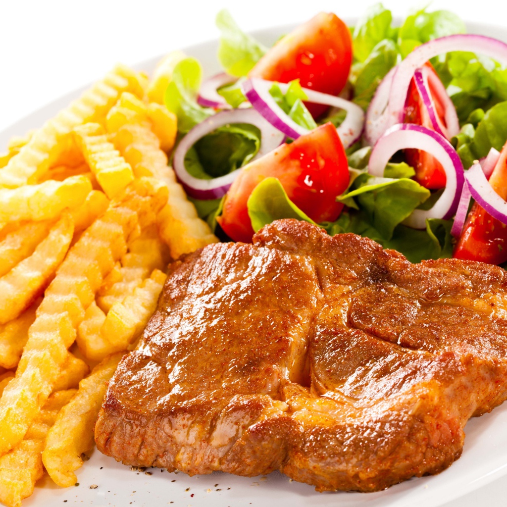 Аппетитная отбивная на тарелке с картофелем фри и салатом