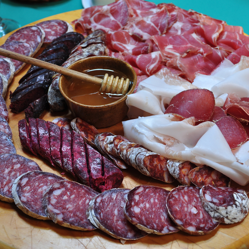 Аппетитная мясная нарезка на разделочной доске с медом