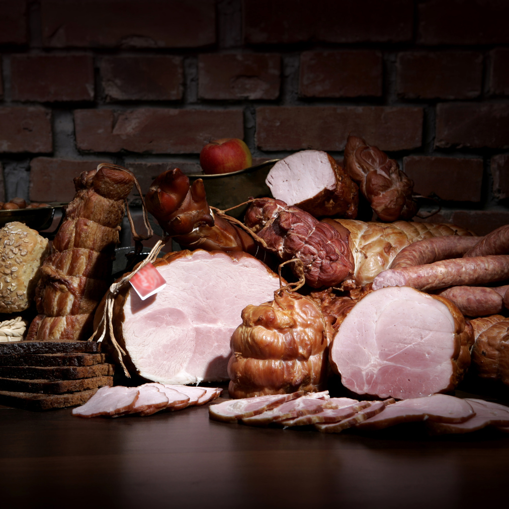Аппетитные мясные продукты на фоне кирпичной стены 