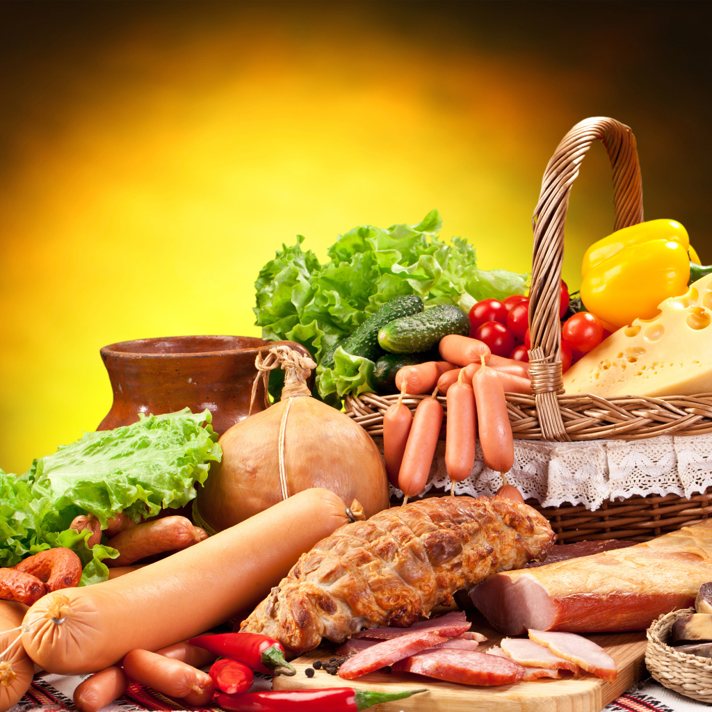 Аппетитные мясные продукты на столе с корзиной овощей