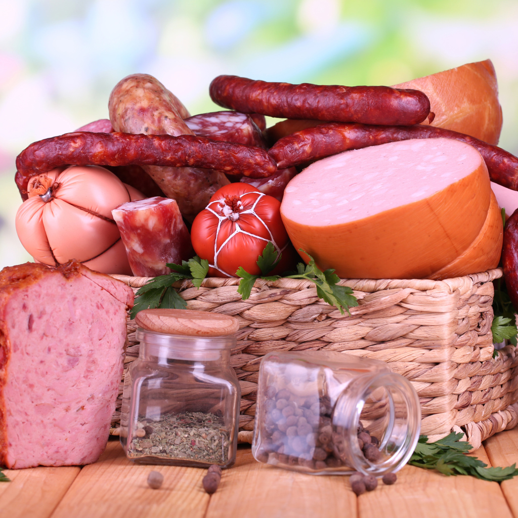 Аппетитная колбаса в корзине на столе со специями