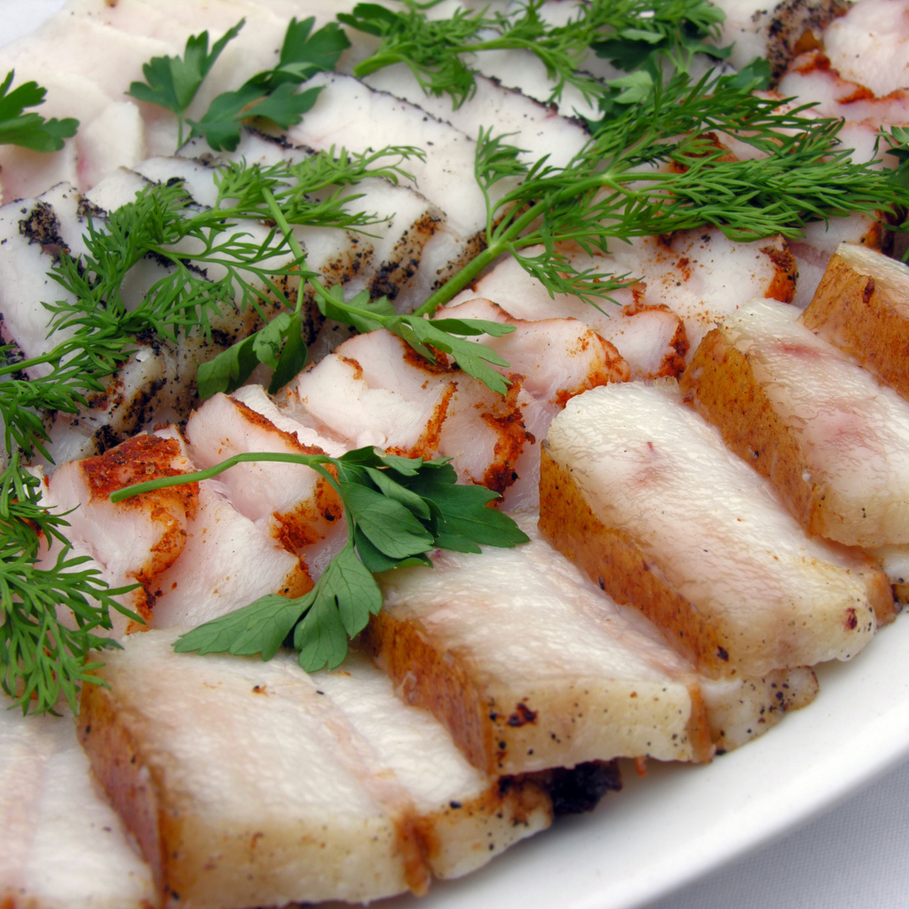 Аппетитное нарезанное копченое сало с зеленью 