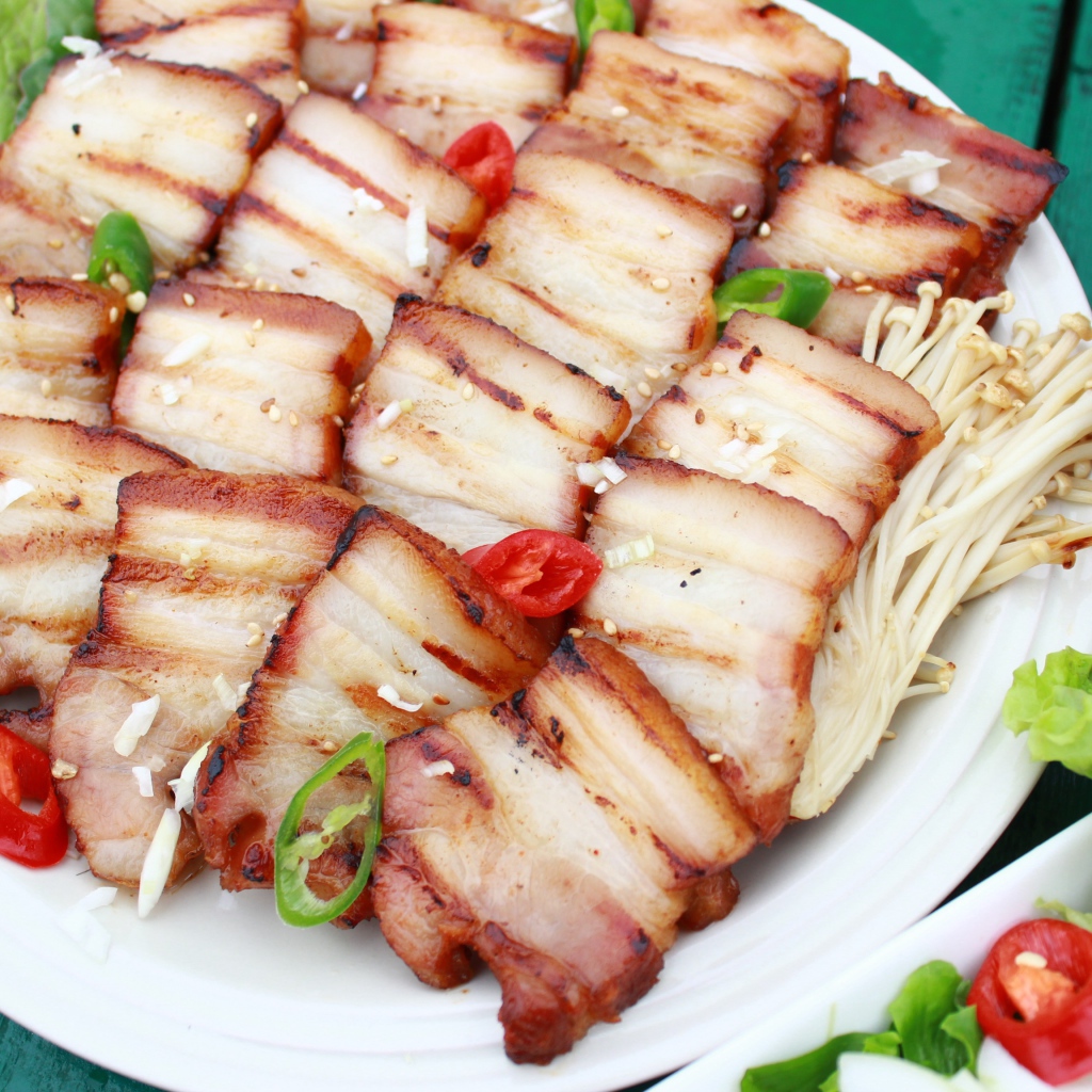 Аппетитное копченое сало на столе с овощами