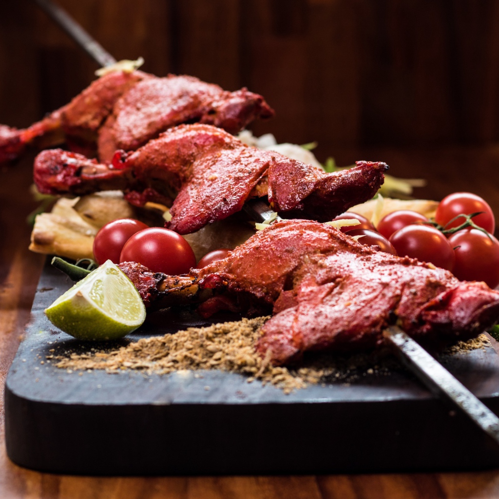 Курица жареная на шампурах на столе с овощами 