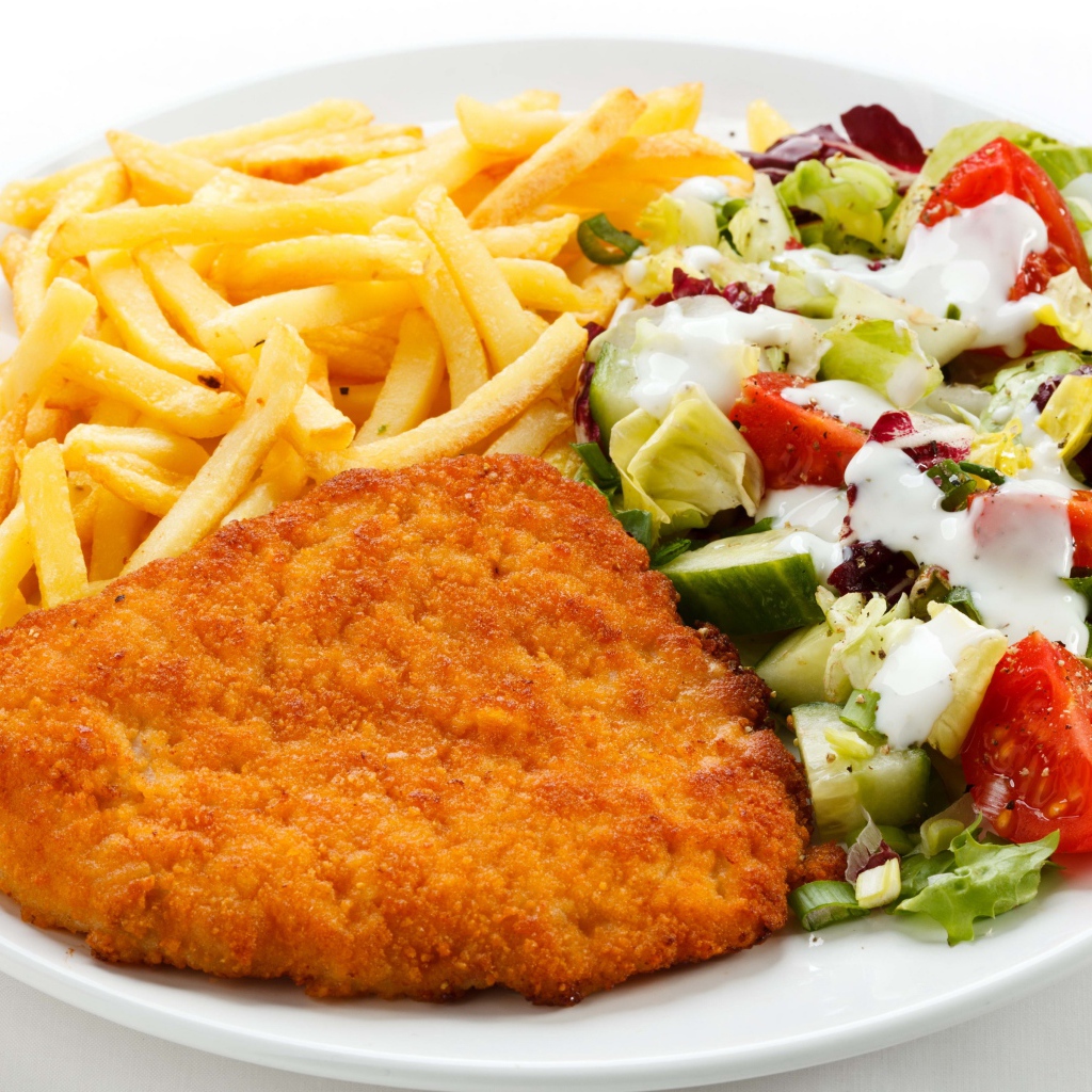 Отбивная на тарелке с картофелем фри и салатом
