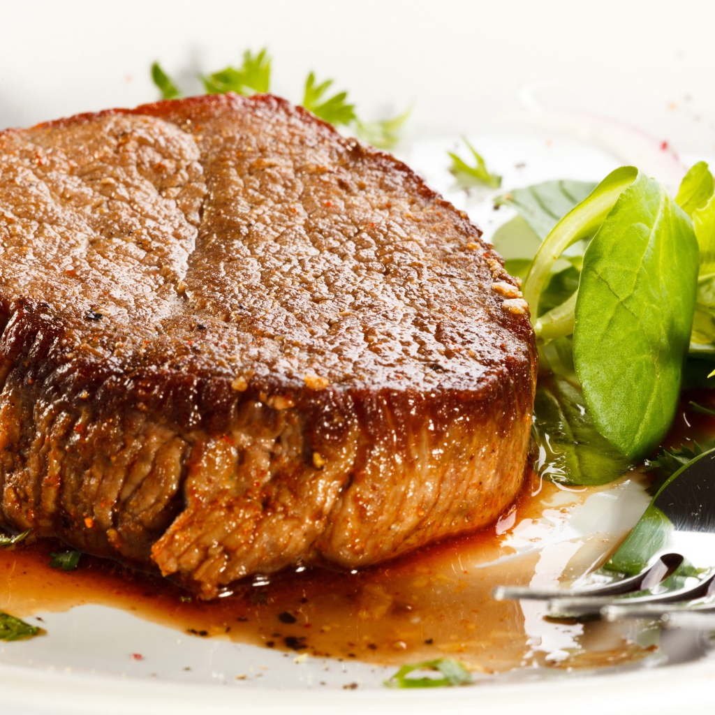 Отбивная с зеленым салатом на тарелке с вилкой