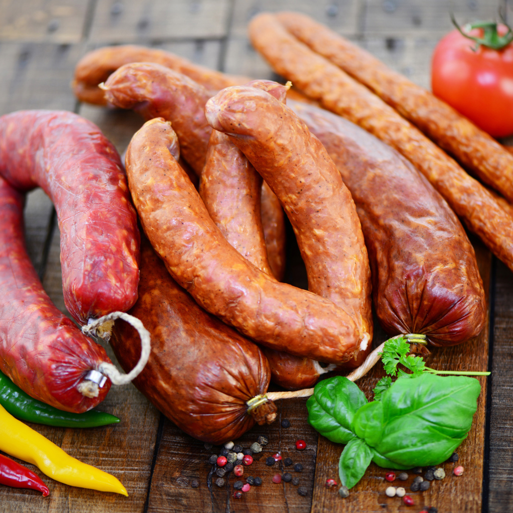Свежие колбасы с перцем на столе