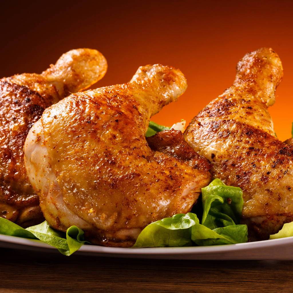 Жареные куриные окорочка на зеленых листьях салата 